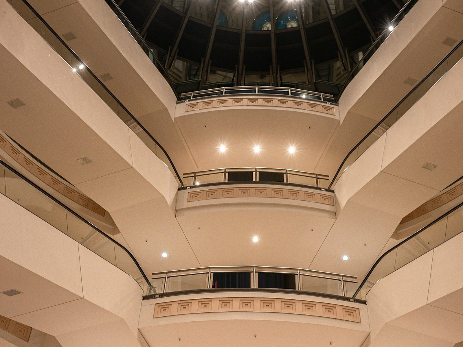 Multi-level shopping centre atrium with curved balconies, glass balustrades and a glazed dome