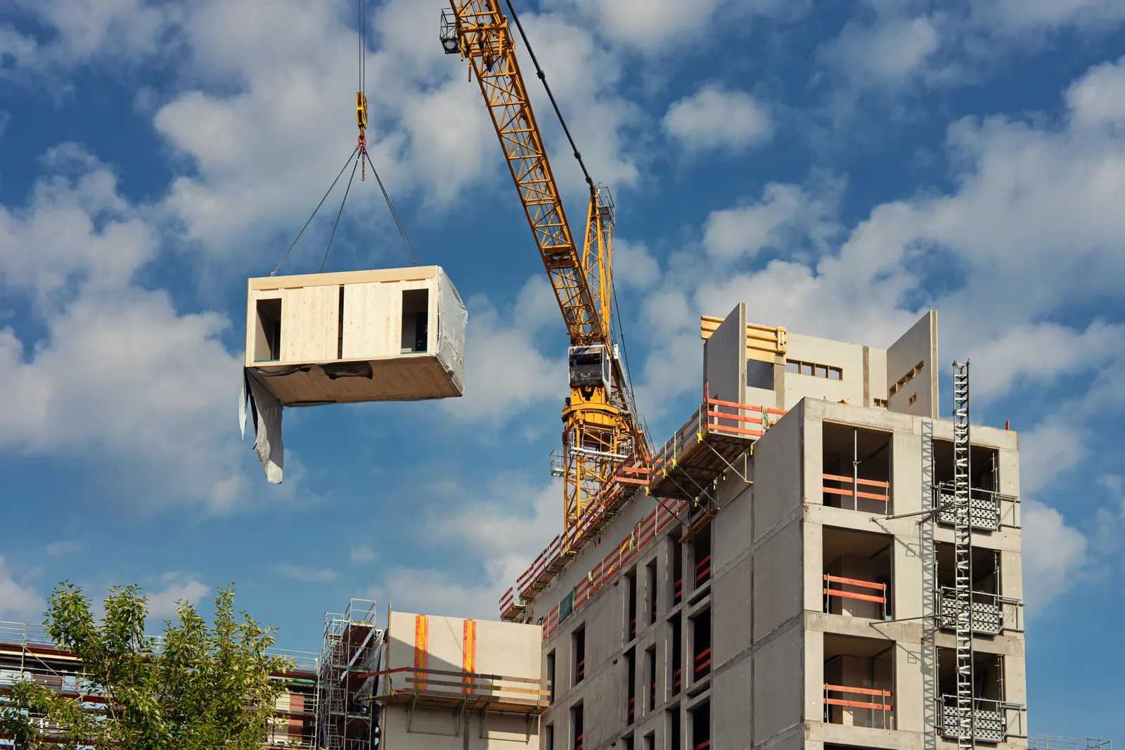 Crane placing a building module onto a multi-storey apartment building